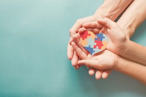 Amn adult and child holding a puzzle heart.