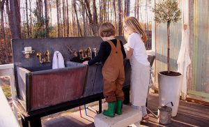 A young boy and girl washing with antique sinks.