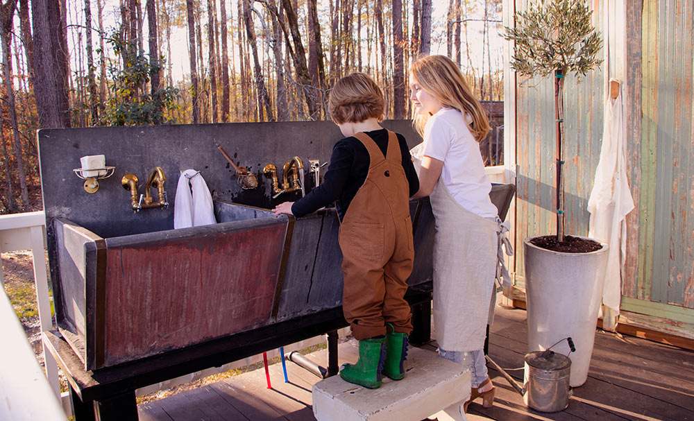 A  young boy and girl washing with antique sinks.