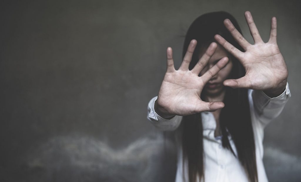 A young woman holds her hands up in self-defense. Illustration for 'Hope, Options and Opportunities Survivors of Trafficking Move Forward'