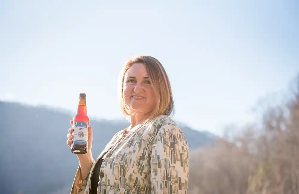 Shanti Volpe holding a bottle of Blueberry Basil Jun from Shanti Elixirs.