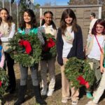 This image displays eight girls who are part of the girl scouts of eastern South Carolina holding wreaths