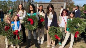 This image displays eight girls who are part of the girl scouts of eastern South Carolina holding wreaths