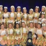 This image displays Pack Athletics Cheerleading team Miss 6 with a trophy after winning the Cheerleading Worlds