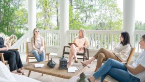 This image displays five women sitting in a semi circle and seem to be discussing something